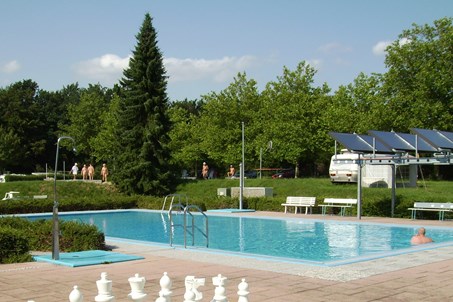 Solarbeheiztes Schwimmbad, dahinter die Gastplätze.